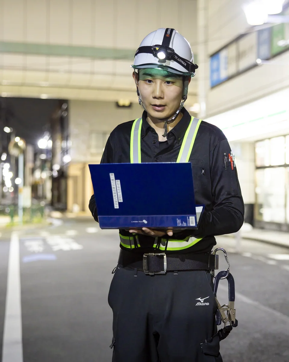 駅の工事現場で資料を確認するSさん