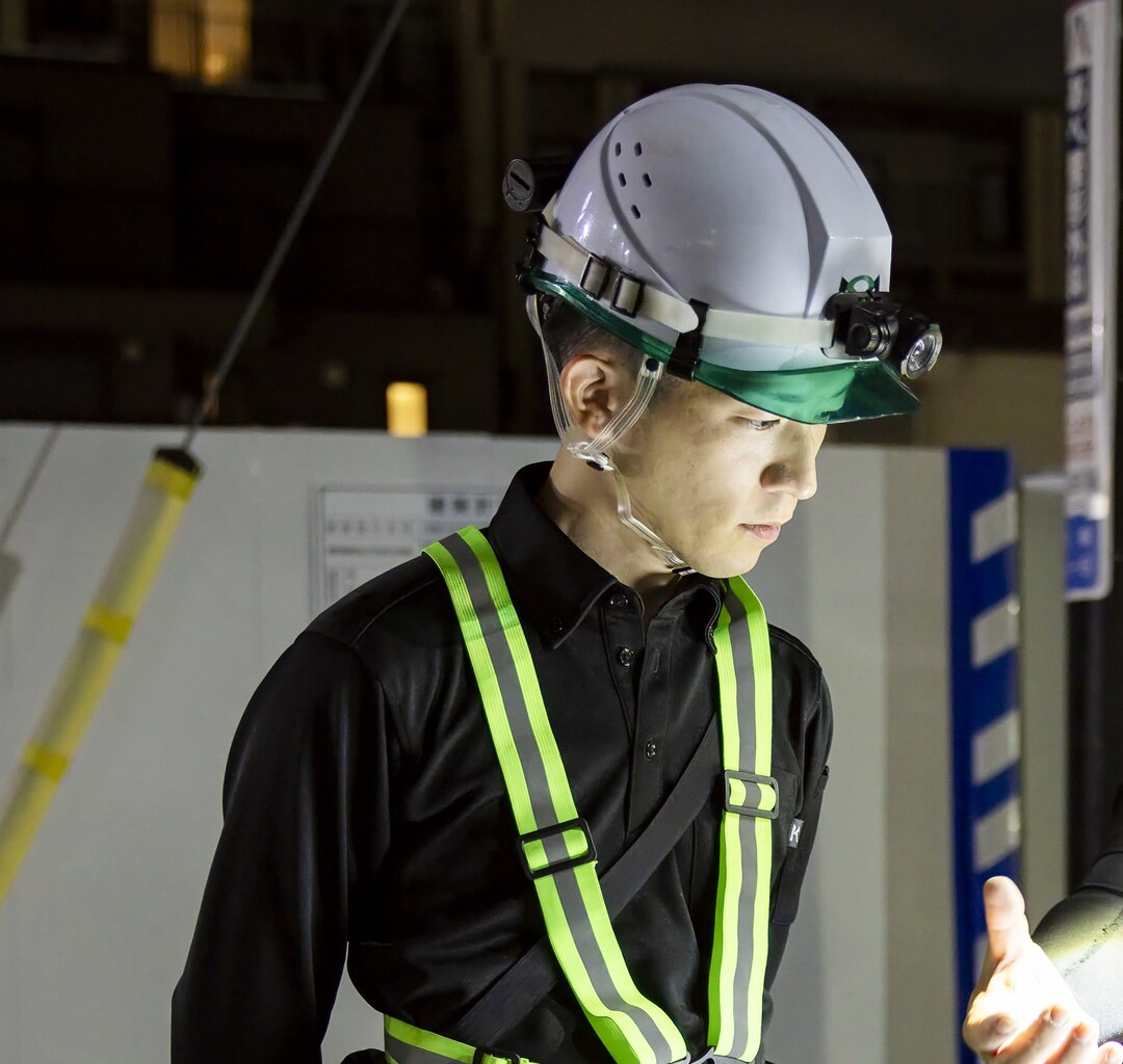 夜間の現場で作業内容を確認する施工管理社員