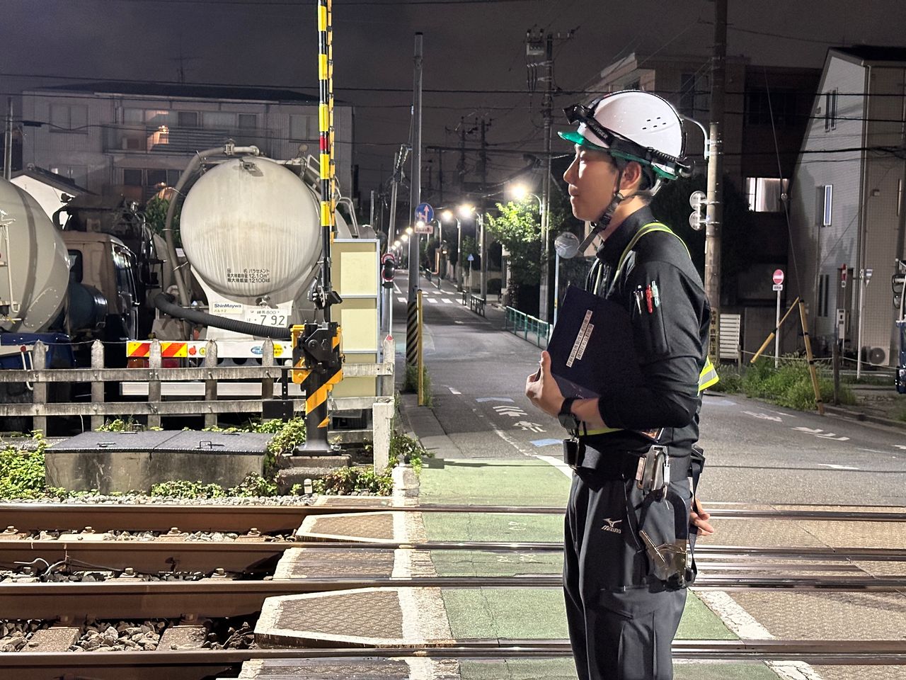 夜間の踏切付近で安全確認を行う作業員