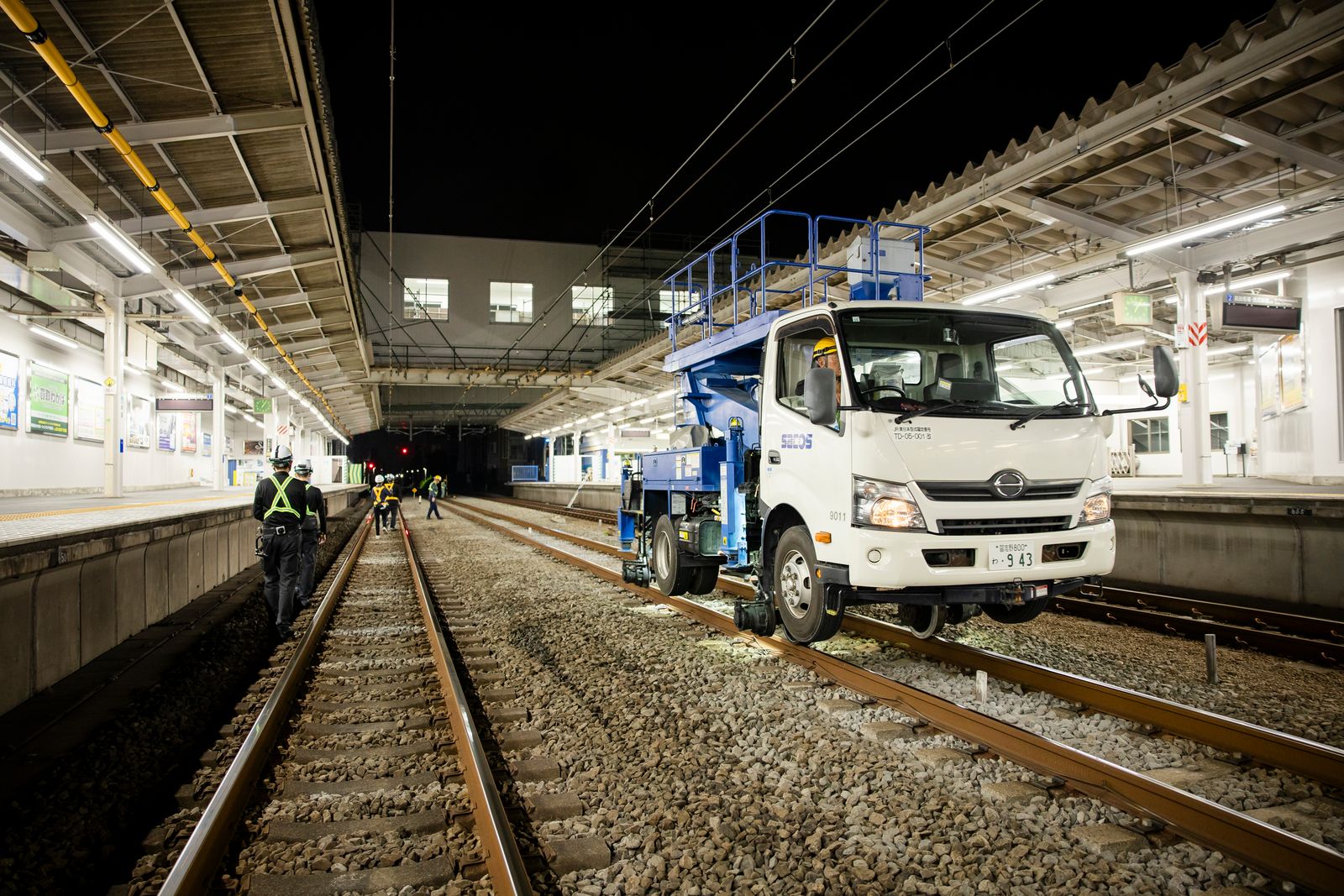 夜間の駅ホームで作業する軌陸車