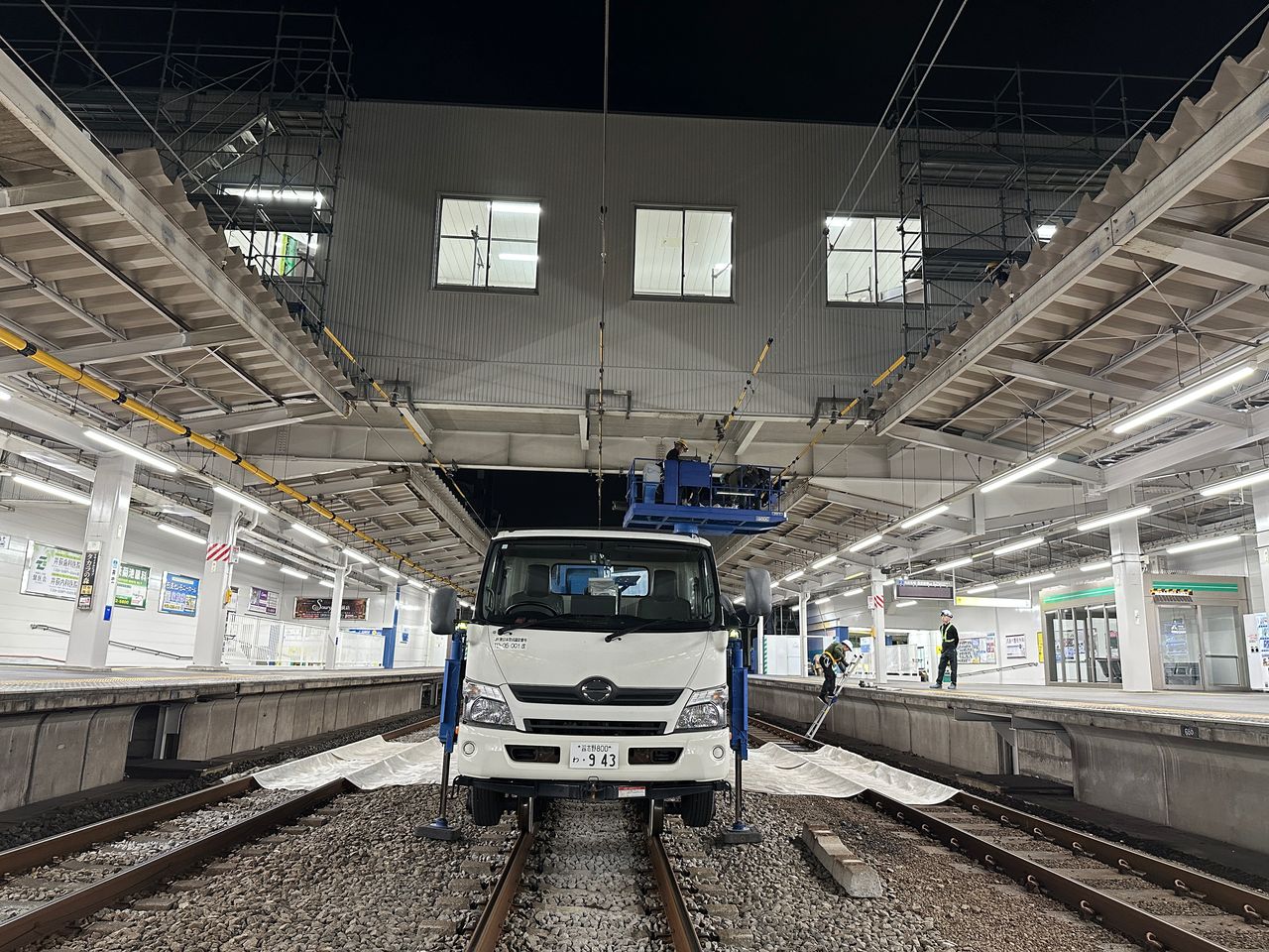 夜間の駅ホームで作業する軌陸車