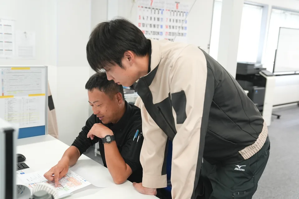 図面を見ながら相談するメンターと若手社員